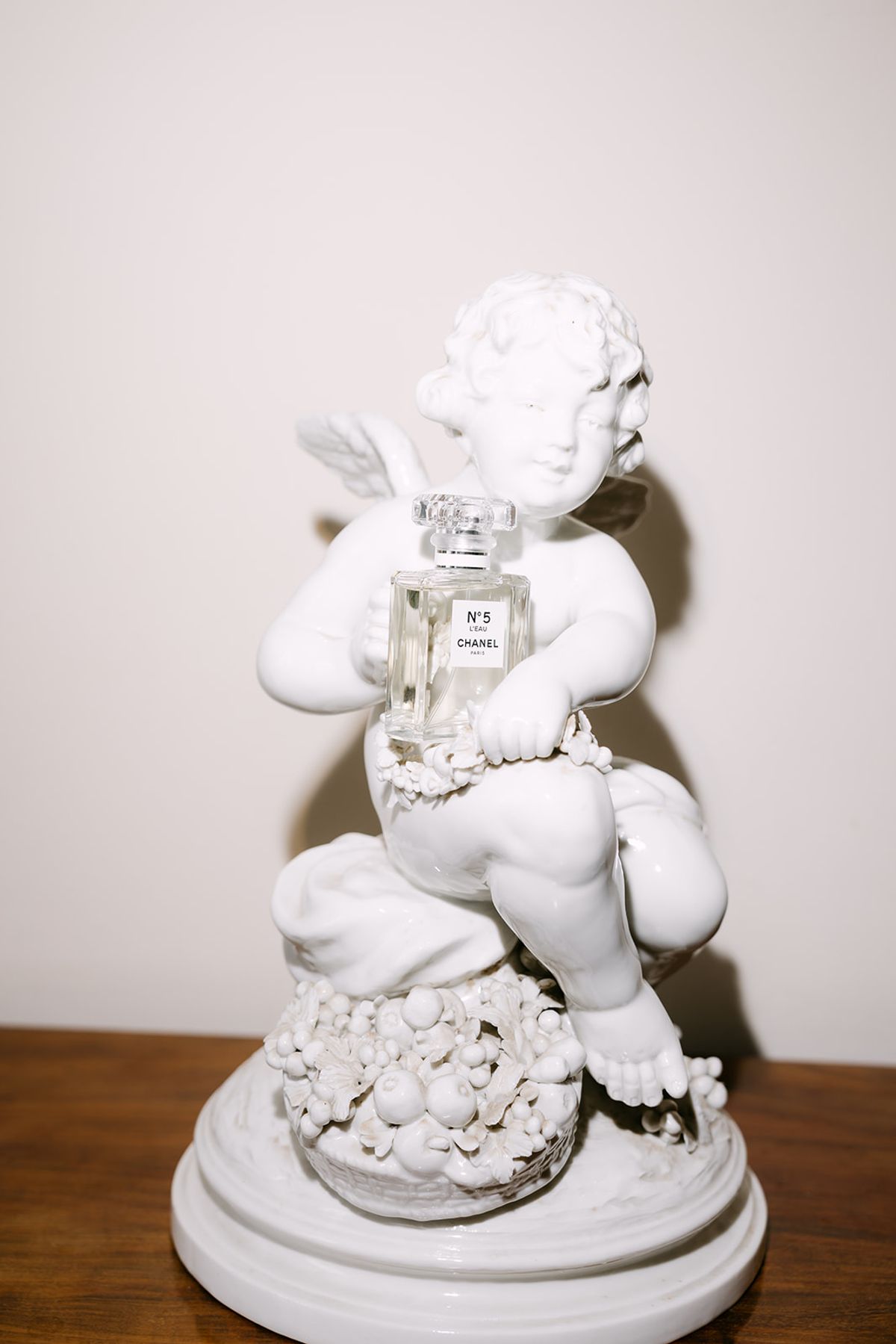 White porcelain cherub figurine holding a perfume bottle
