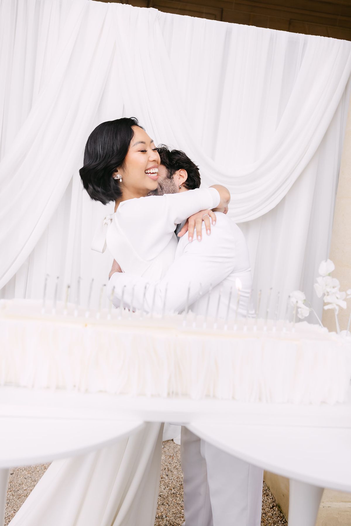 Bride and groom hugging behind the long white cake