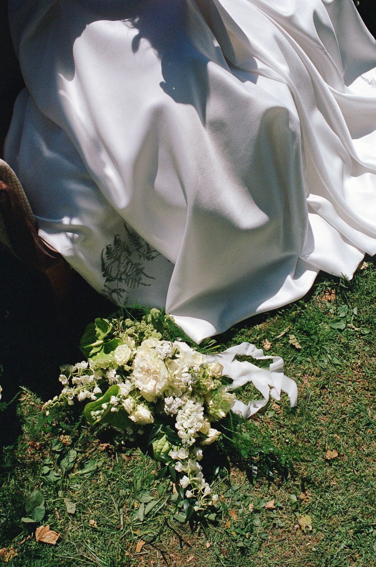 Wedding gown draped over an antique chair, floral train catching the light, shot on film