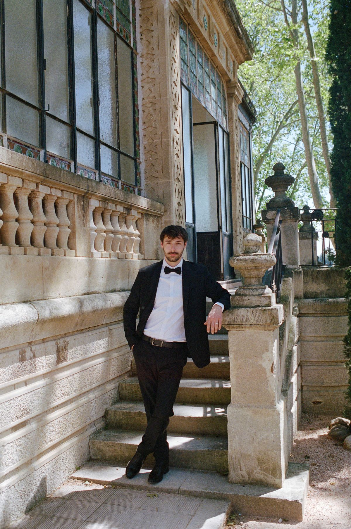 Groom leaning against a stone balustrade on the chateau staircase