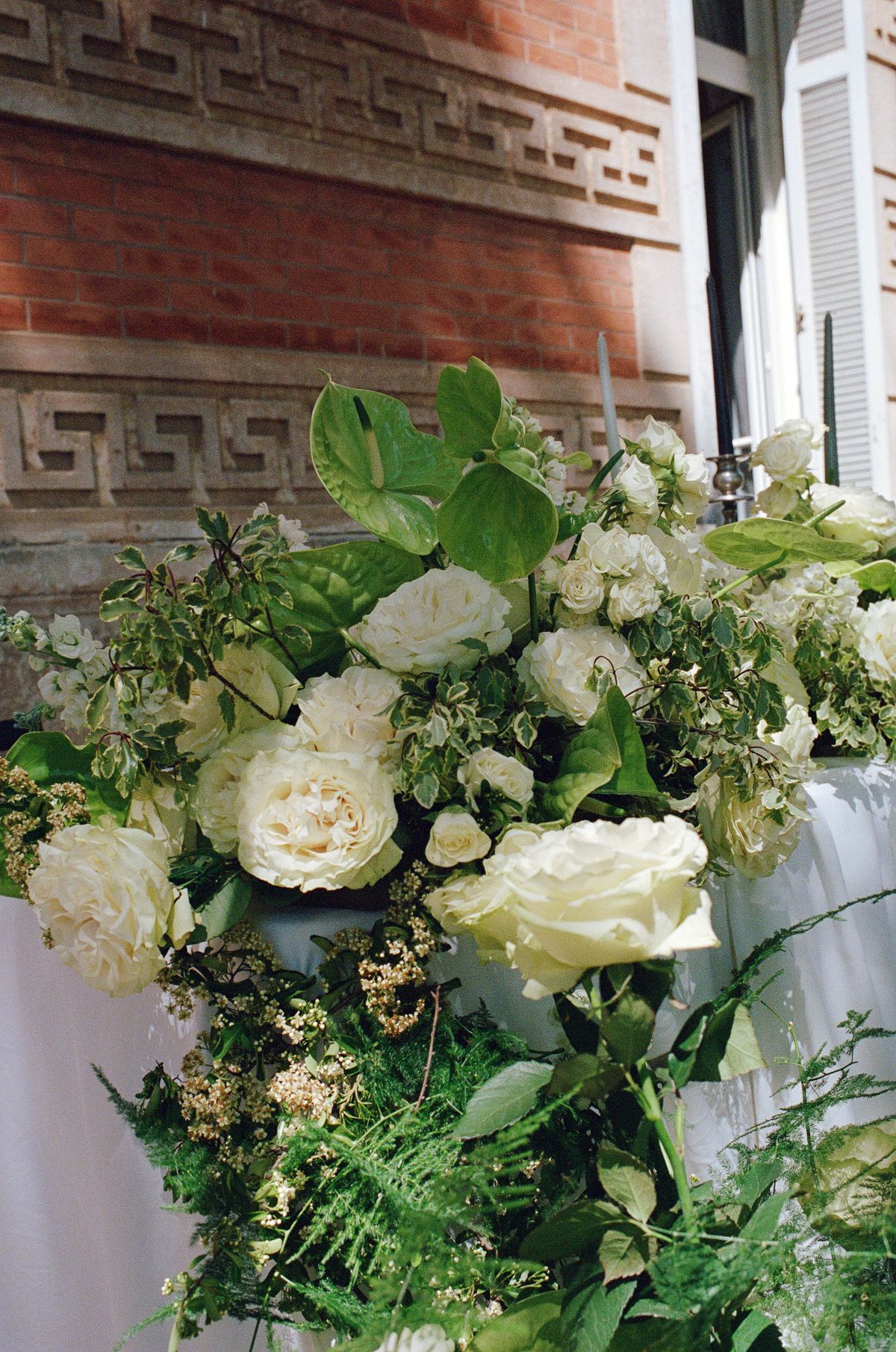 Arrangement of white roses and broad green foliage on a table edge