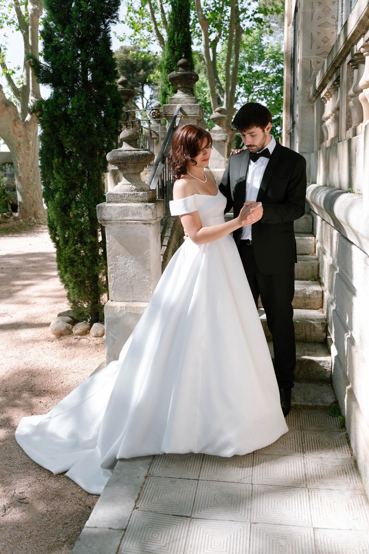 Bride and groom standing close together on the chateau's stone staircase