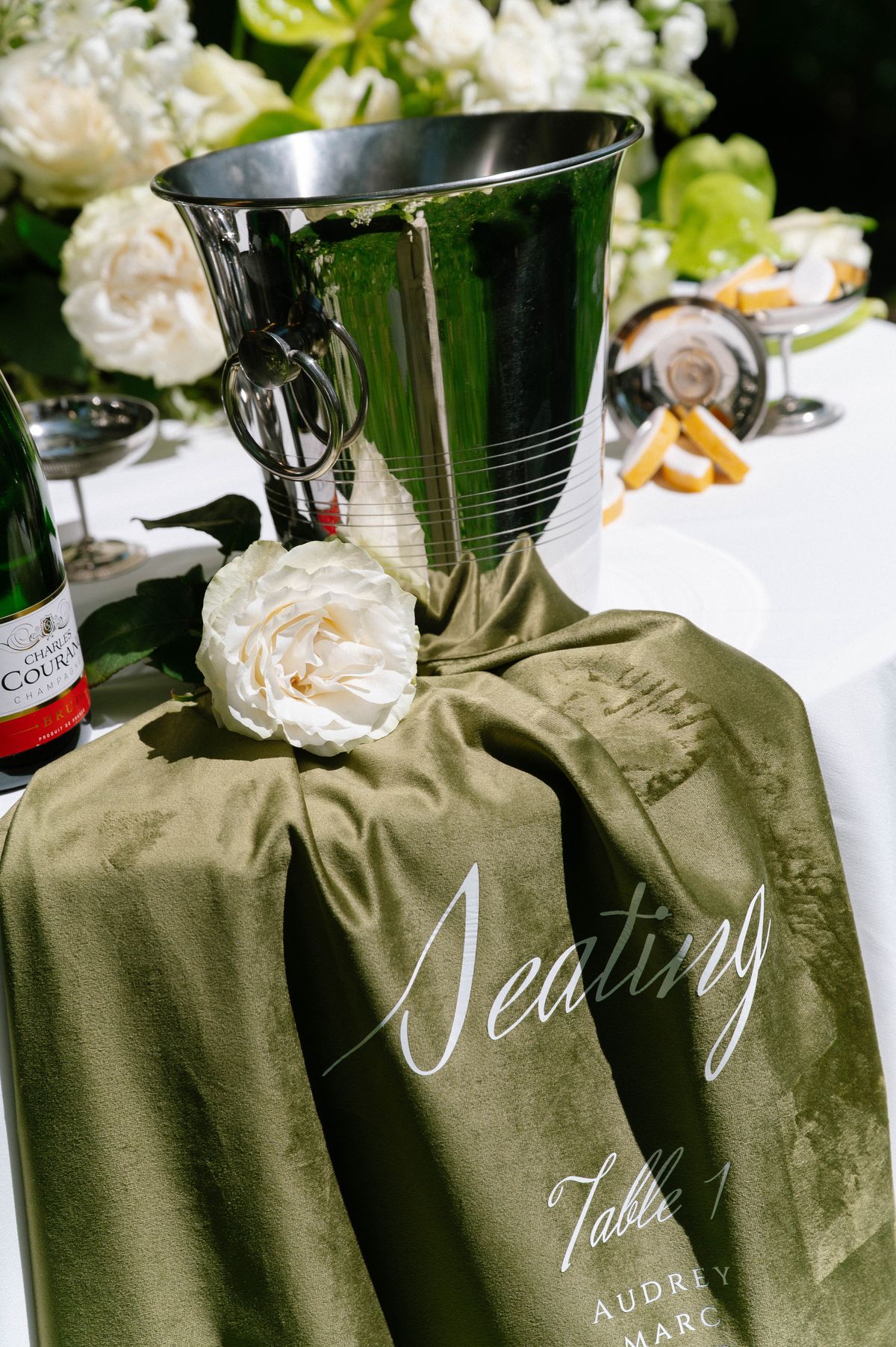 Champagne coupes and a white rose styled beside a green silk ribbon detail