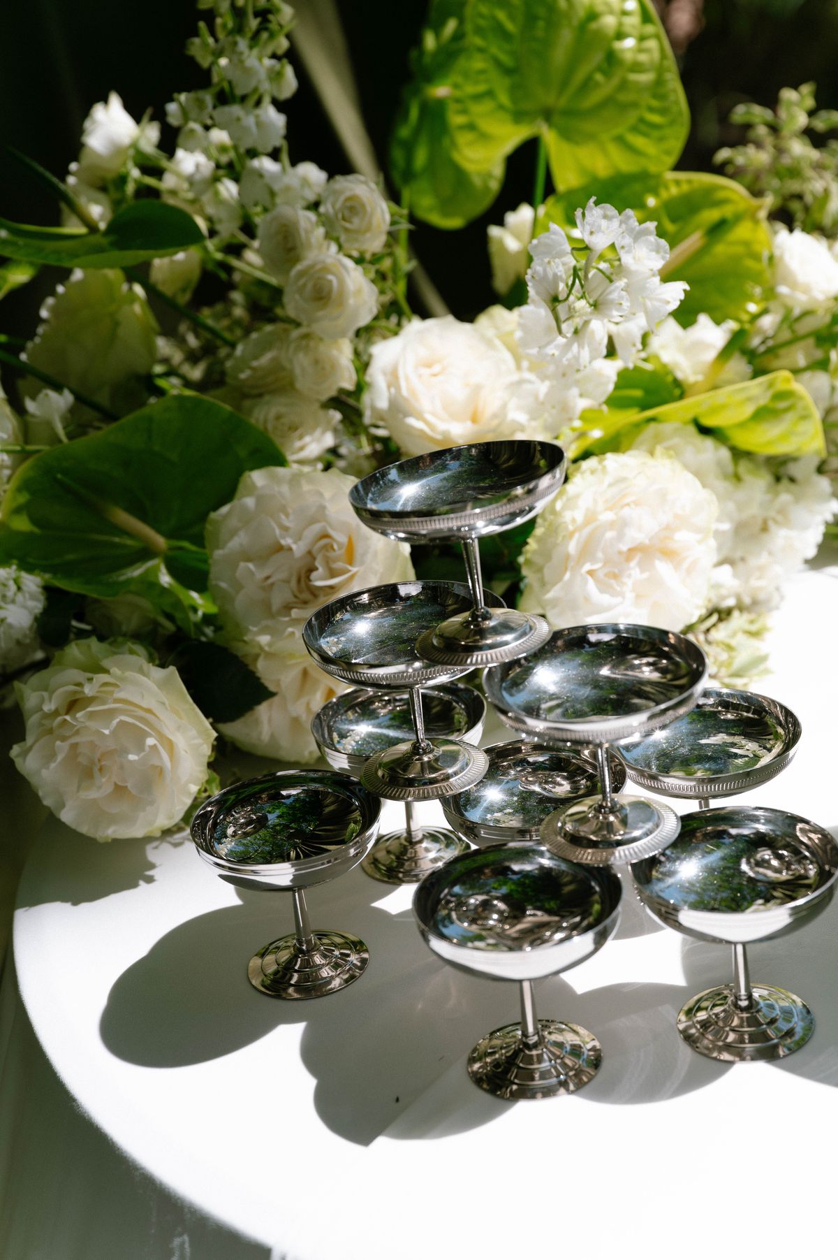 Tiered silver coupe stand styled with white roses for a champagne display
