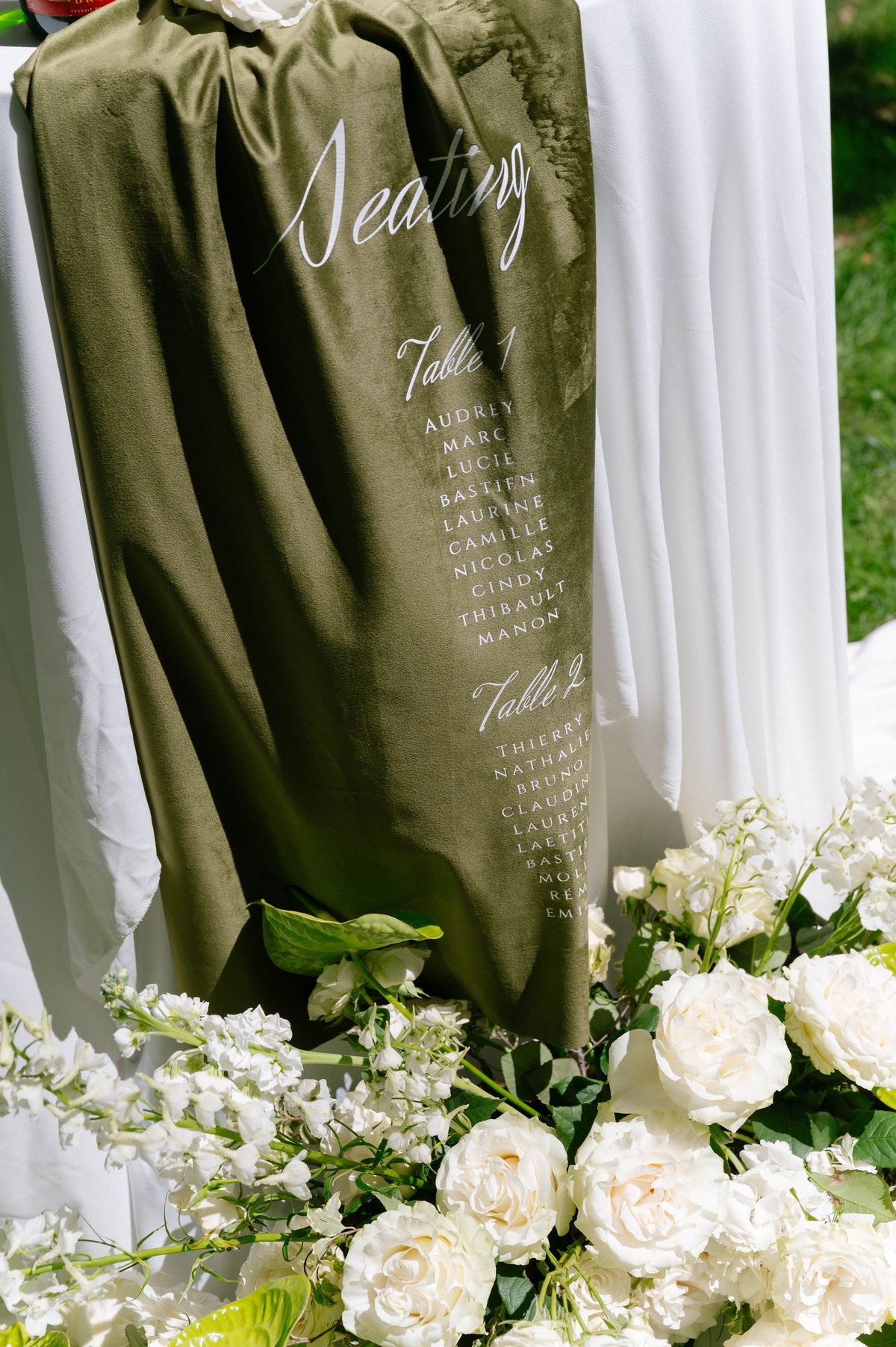 Dark green table runner embroidered with guest names, styled with white florals