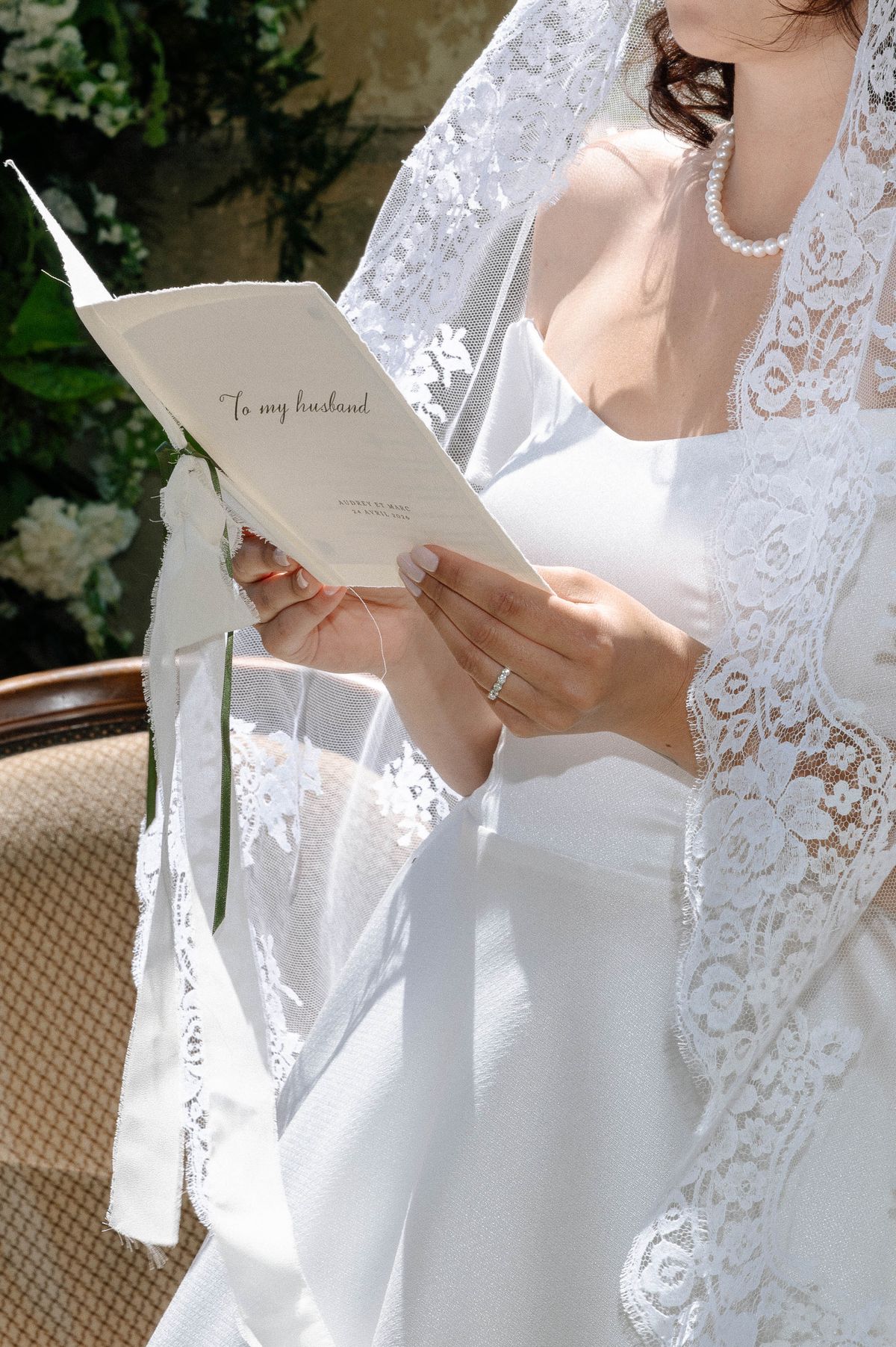 Handwritten vow note reading 'To my husband' held beside a lace veil