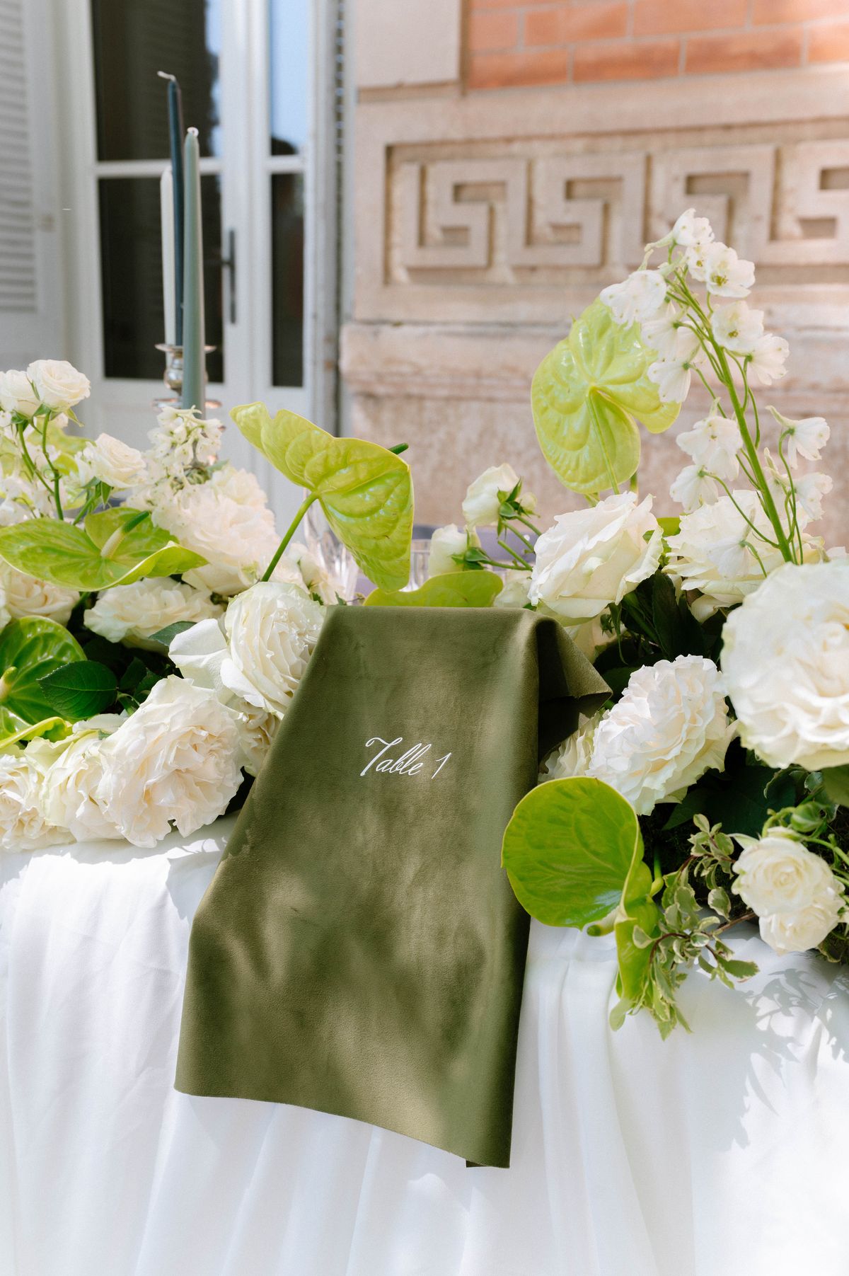 Green velvet table-plan book reading 'Table 1' styled with white roses