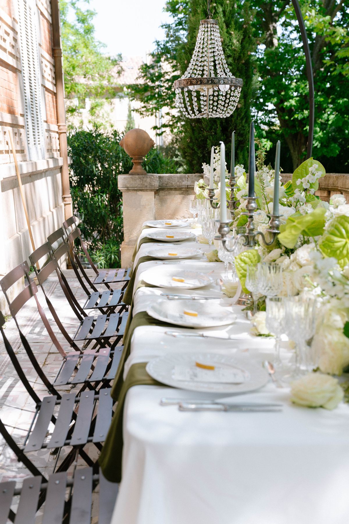 Long reception table set outdoors on a stone terrace with candelabra and white linens