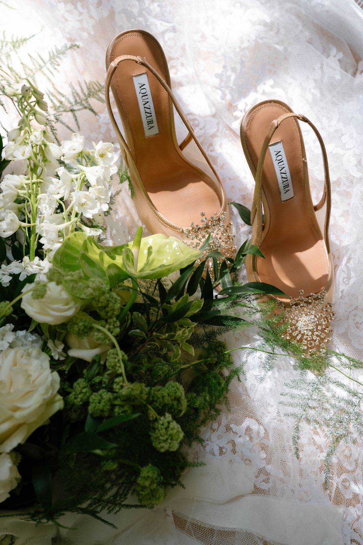 Close detail of a beaded heel resting among white and green florals