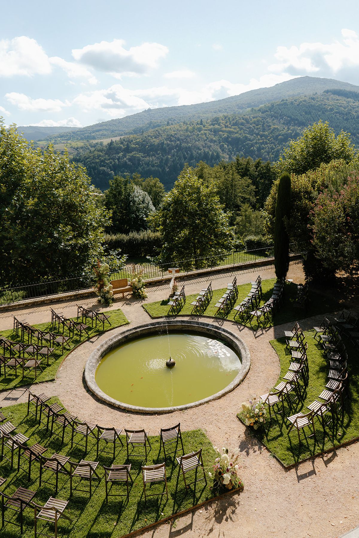 Ceremony chairs set in a circle around the garden pool, with the Beaujolais hills beyond