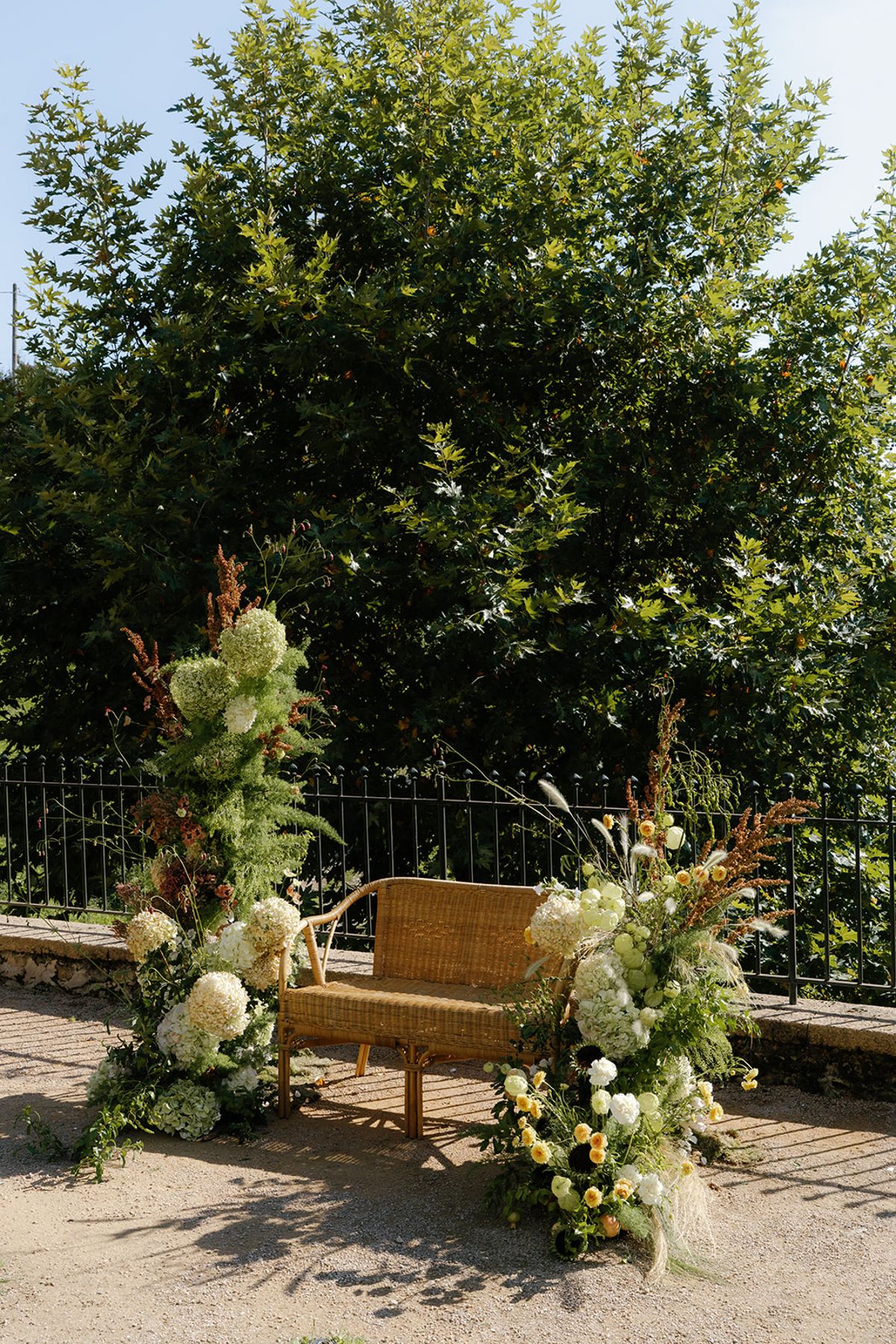 Loose seasonal florals framing the ceremony bench