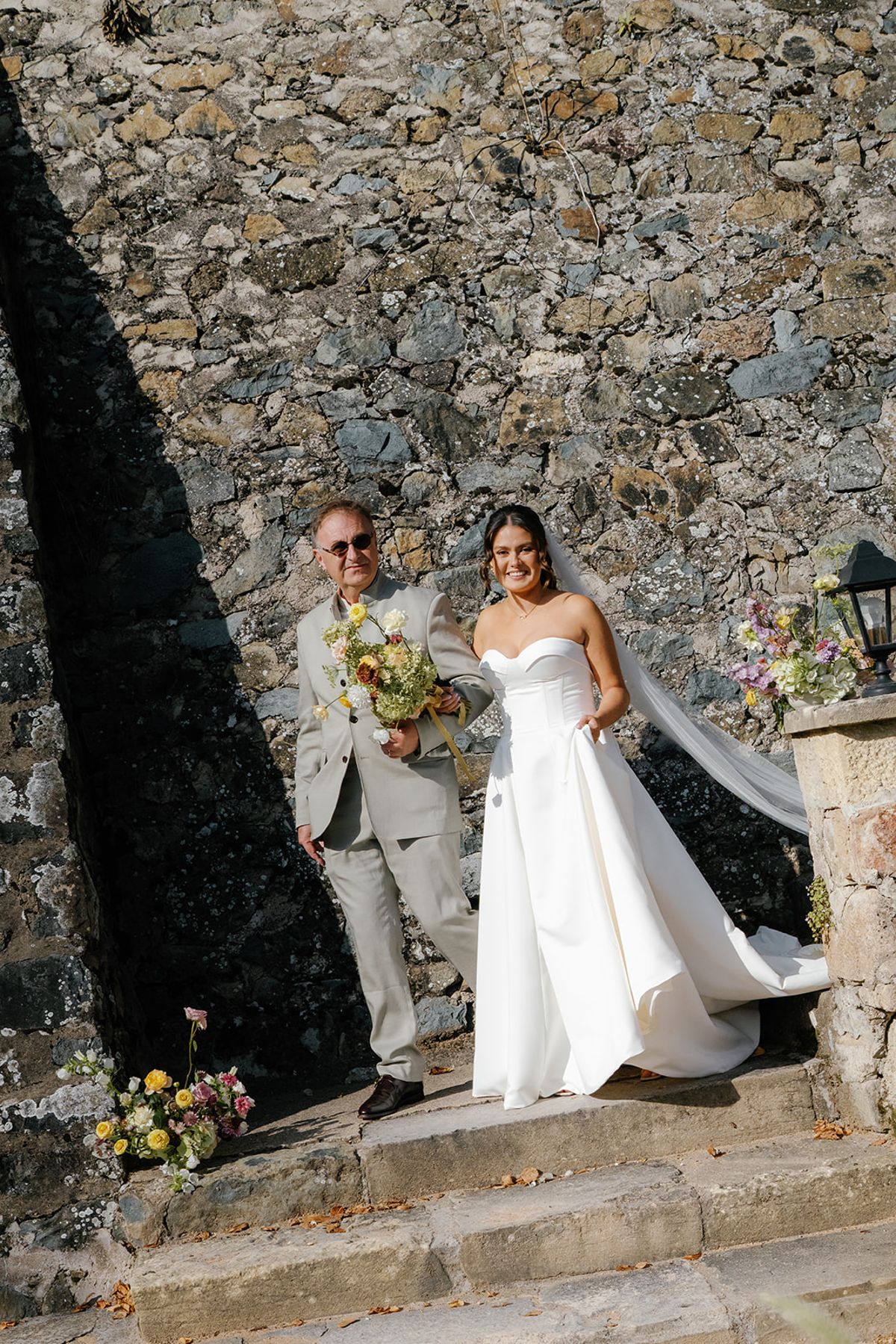 The bride walking down the stone steps towards the ceremony