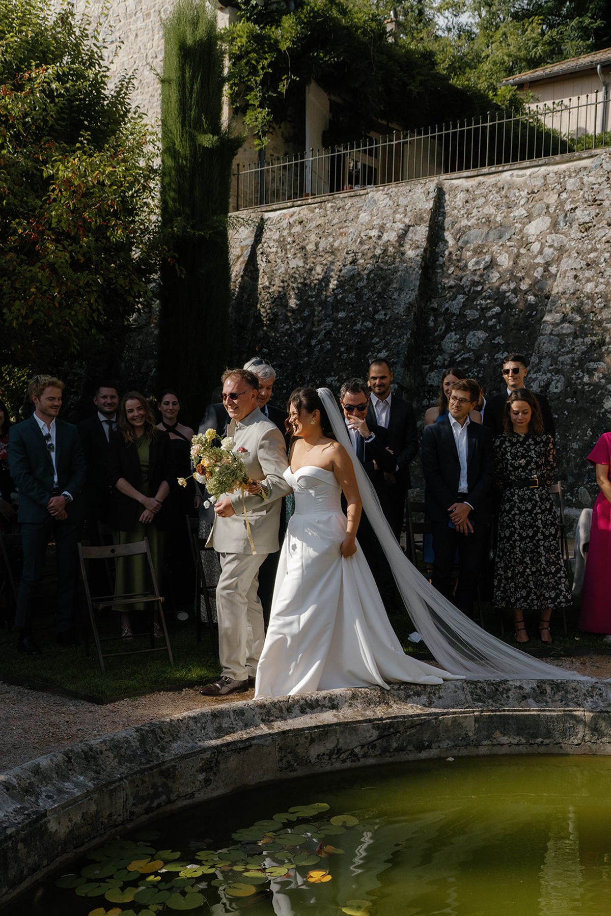 The couple at the poolside ceremony with their guests standing