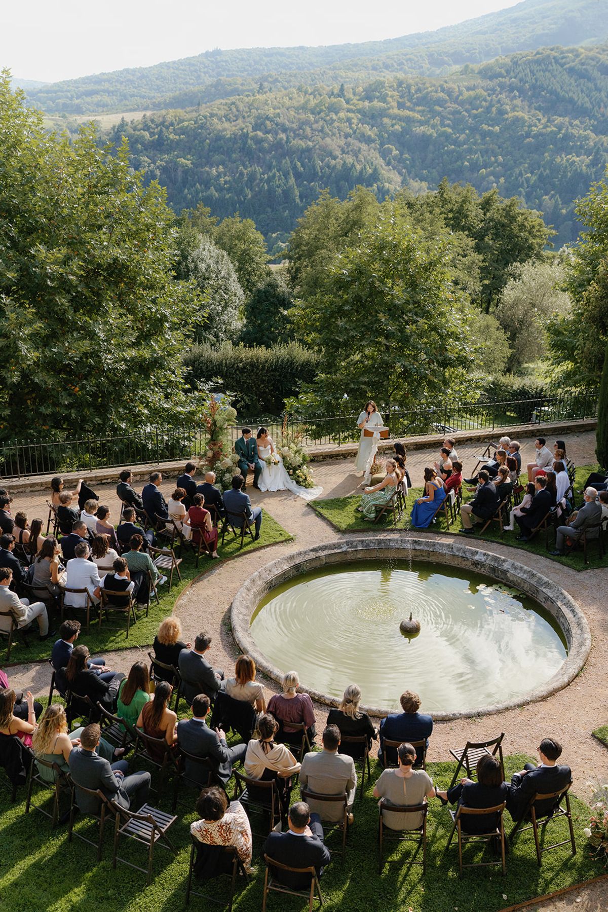 The outdoor ceremony seen across the garden pool