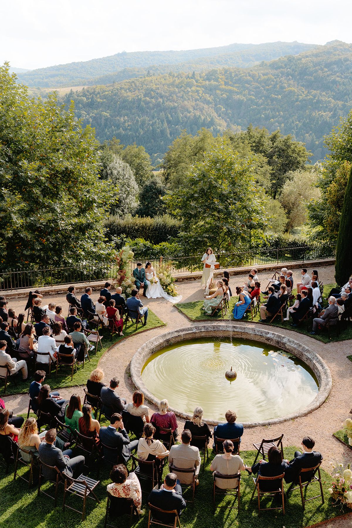 Guests seated around the circular pool for the ceremony