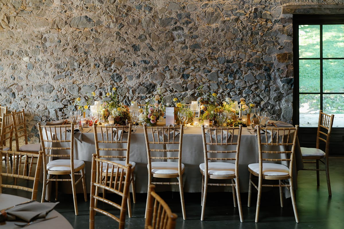 The long dinner table set in the stone reception room