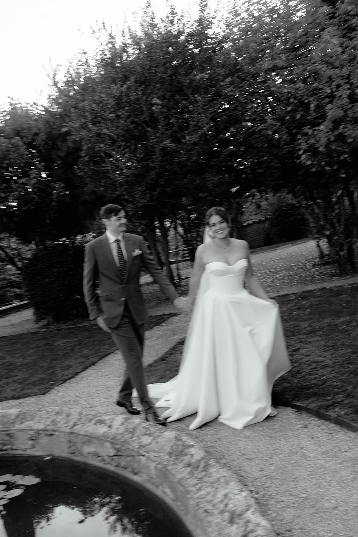 Claire and Baptiste walking beside the garden pool in black and white