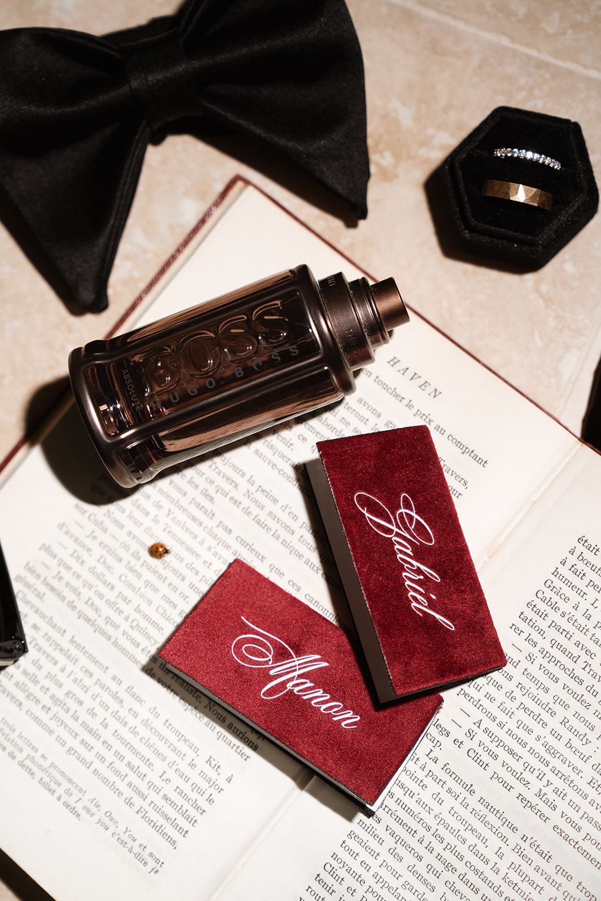 Bow tie, cologne, ring box and burgundy matchboxes on an open book