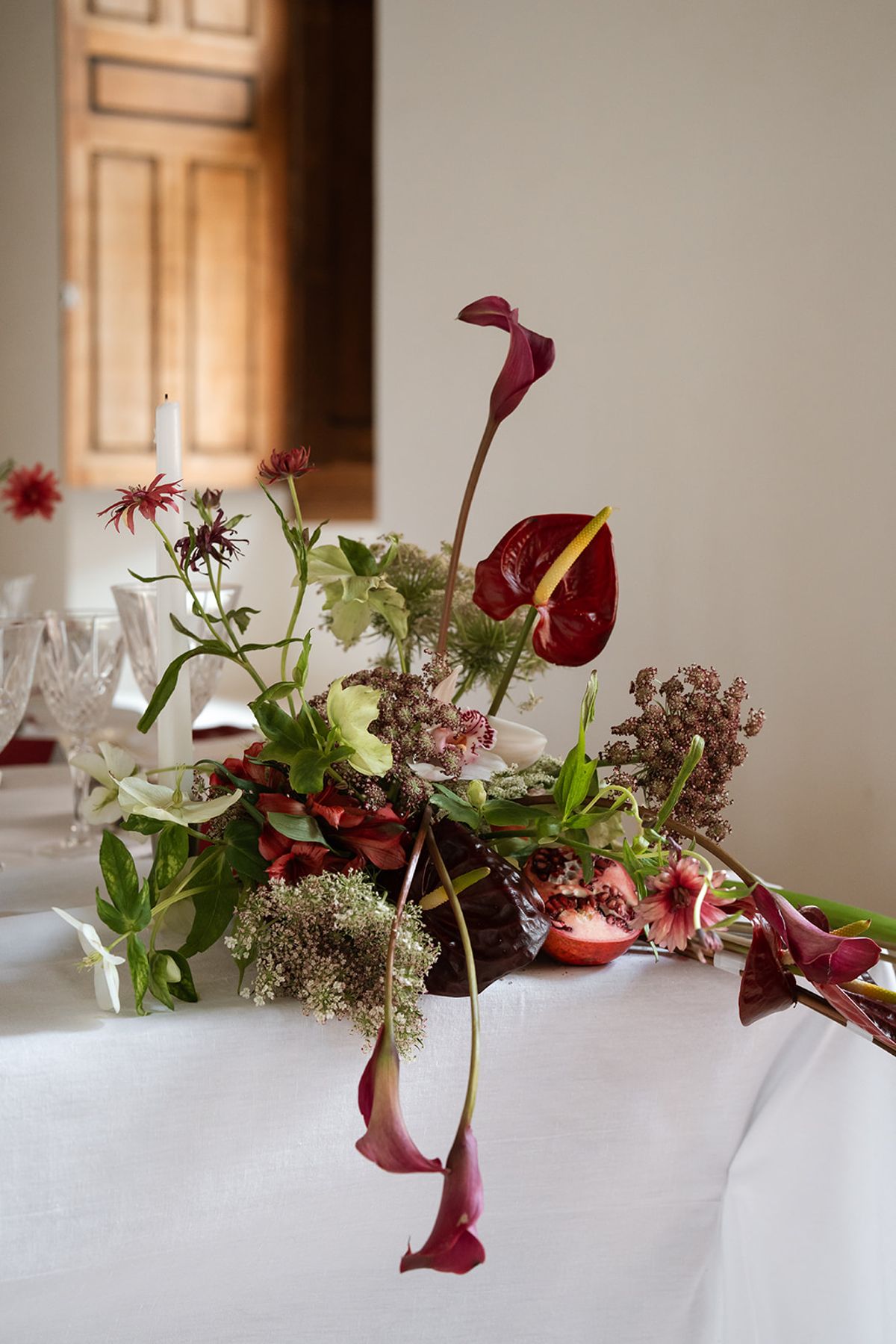 Burgundy anthurium and calla lily centrepiece on a white tablecloth