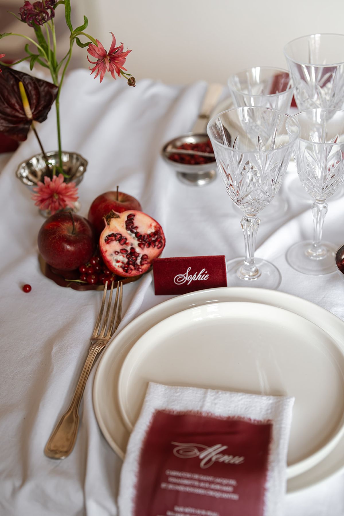 Place setting with pomegranates, a calligraphy name card and a burgundy menu