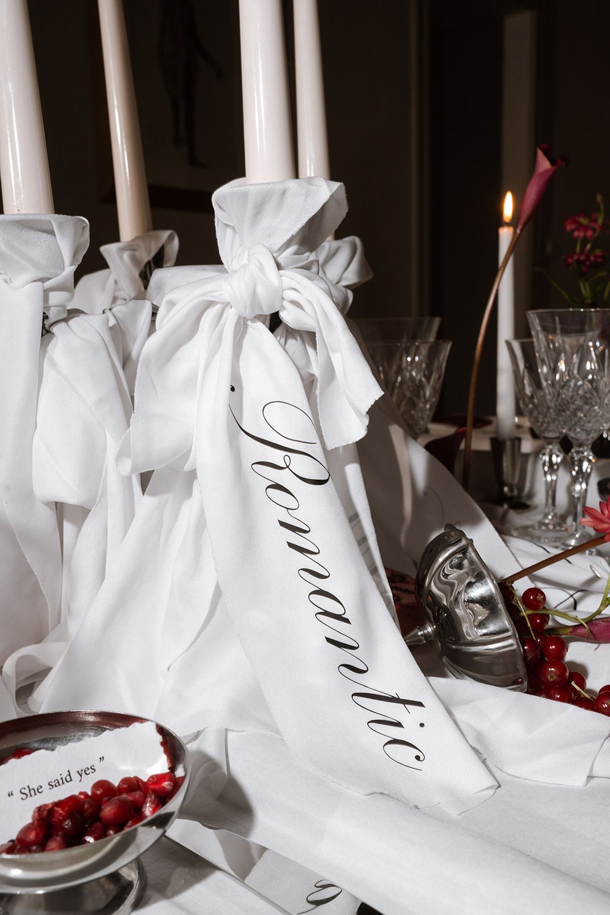 Candles wrapped in white fabric tied with a ribbon lettered Romantic
