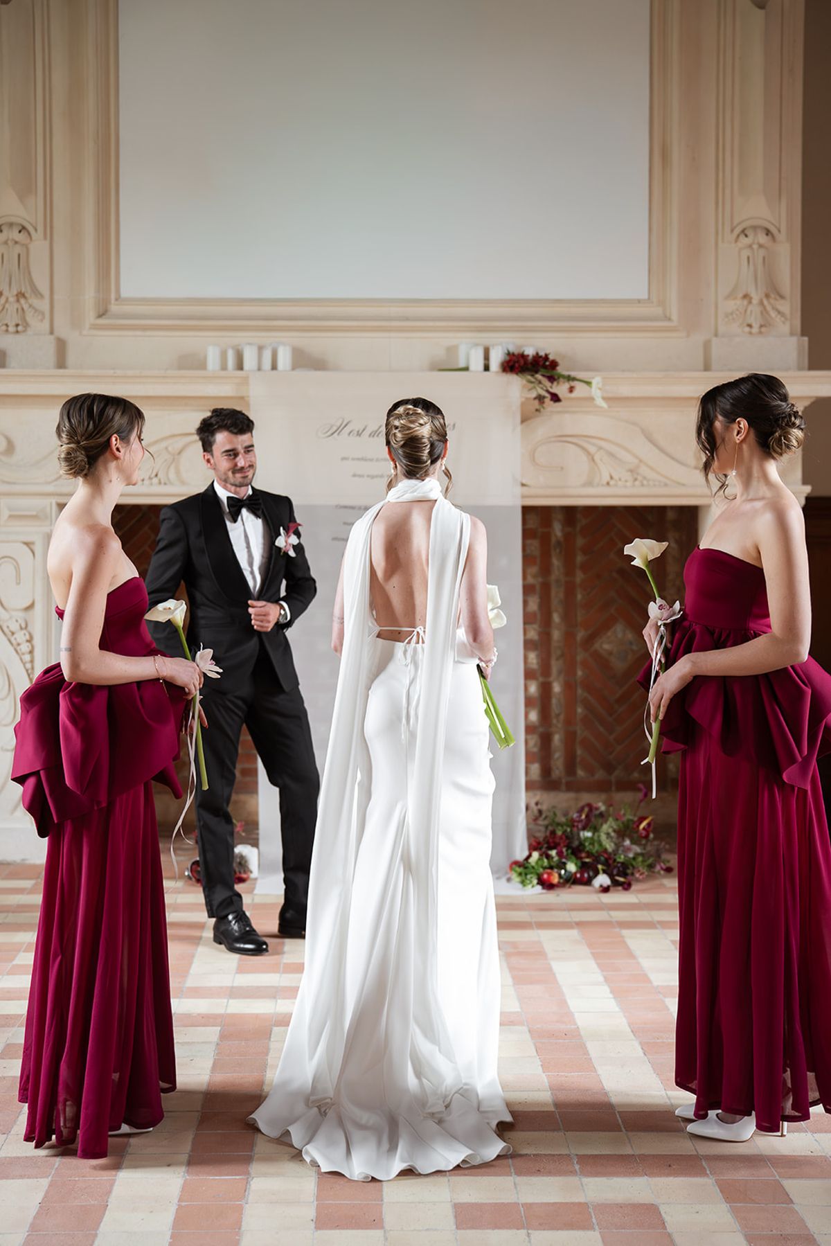 Bride and groom at the ceremony seen from behind, between two bridesmaids