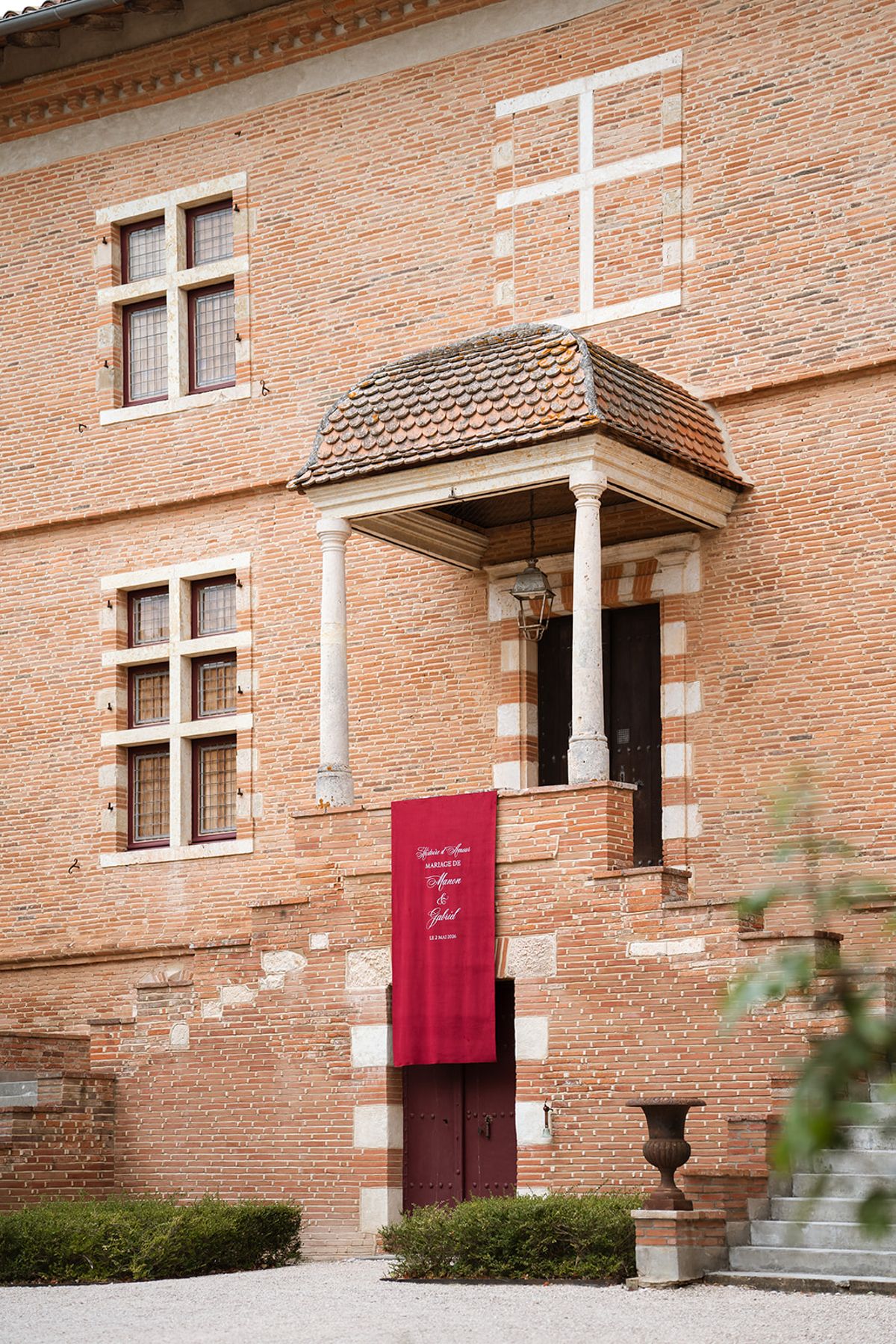 Brick façade of Château de Savignac-Mona with a burgundy welcome banner at the door