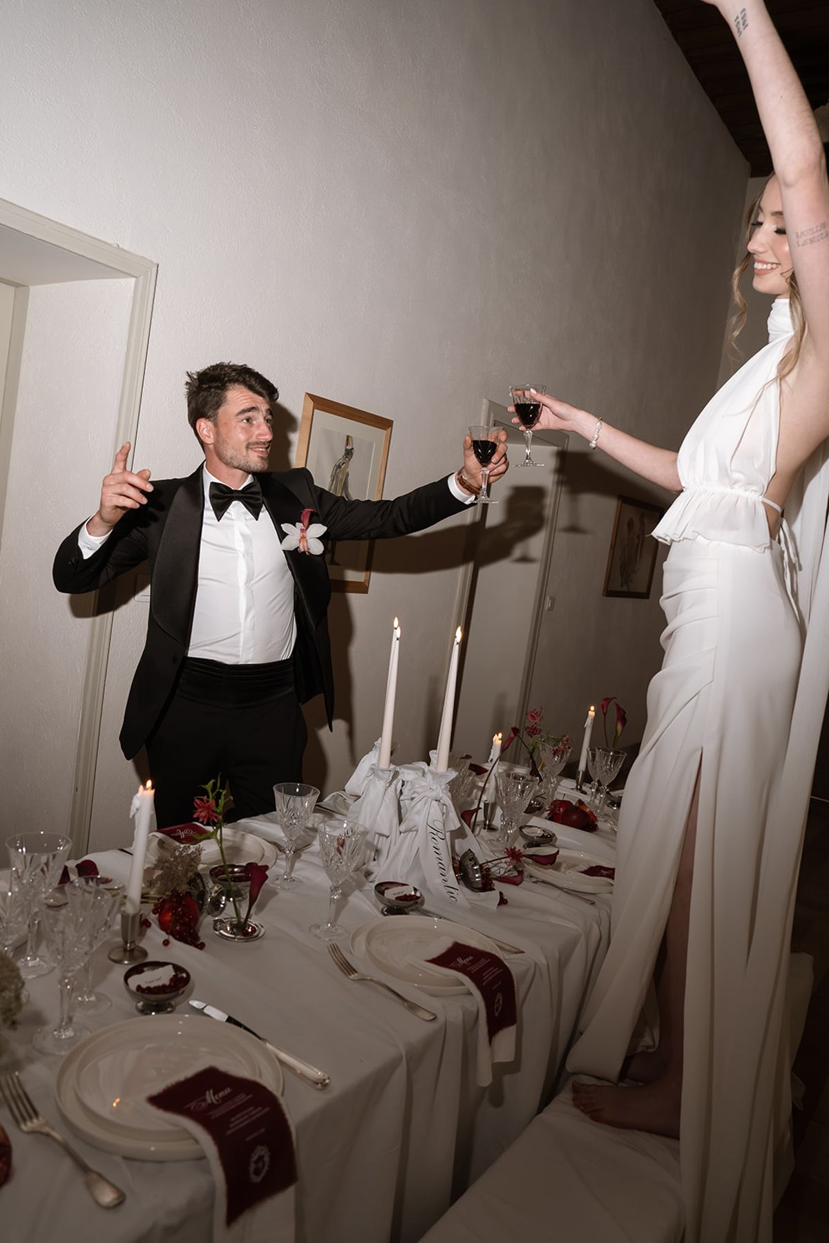 Bride and groom raising their glasses across the dinner table
