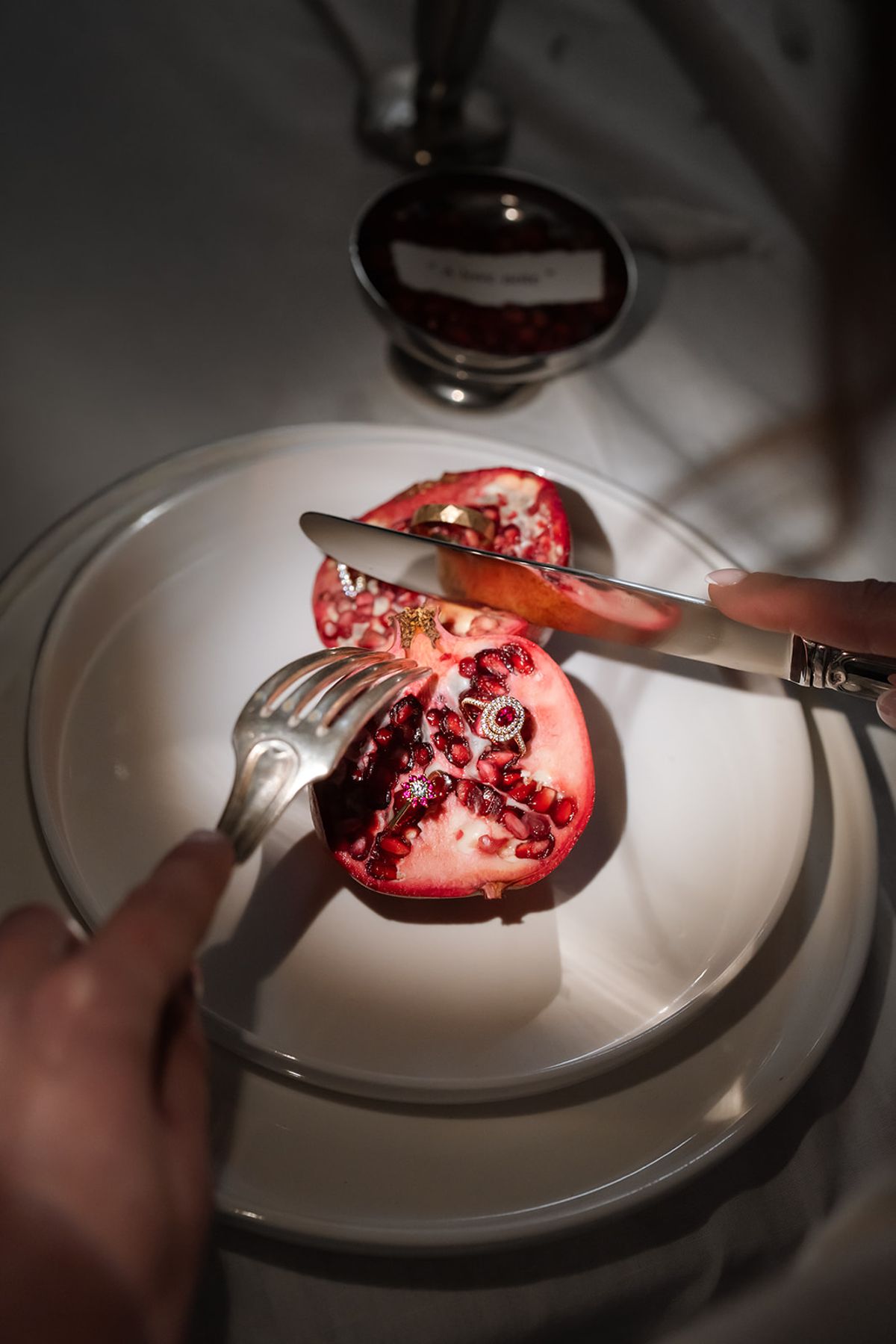 Pomegranate being cut on a white plate
