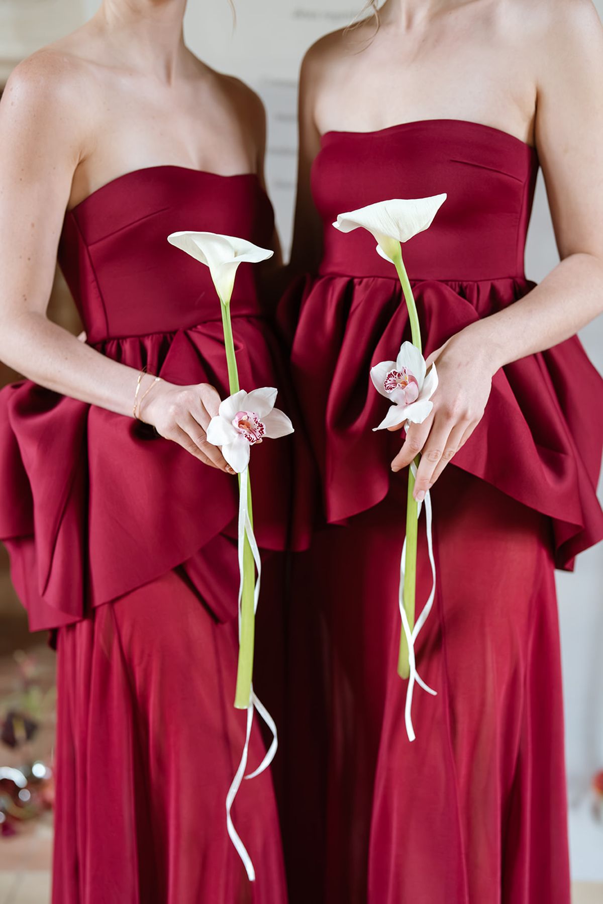 Two bridesmaids in burgundy holding calla lilies and orchids