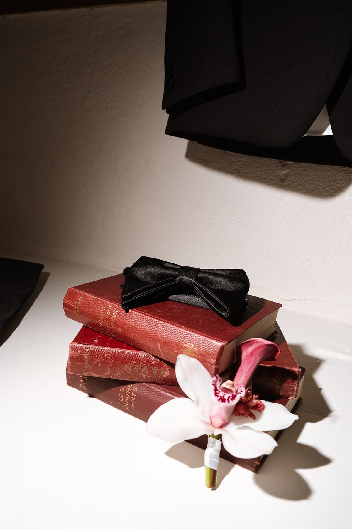 Black bow tie and orchid boutonnière resting on old leather books