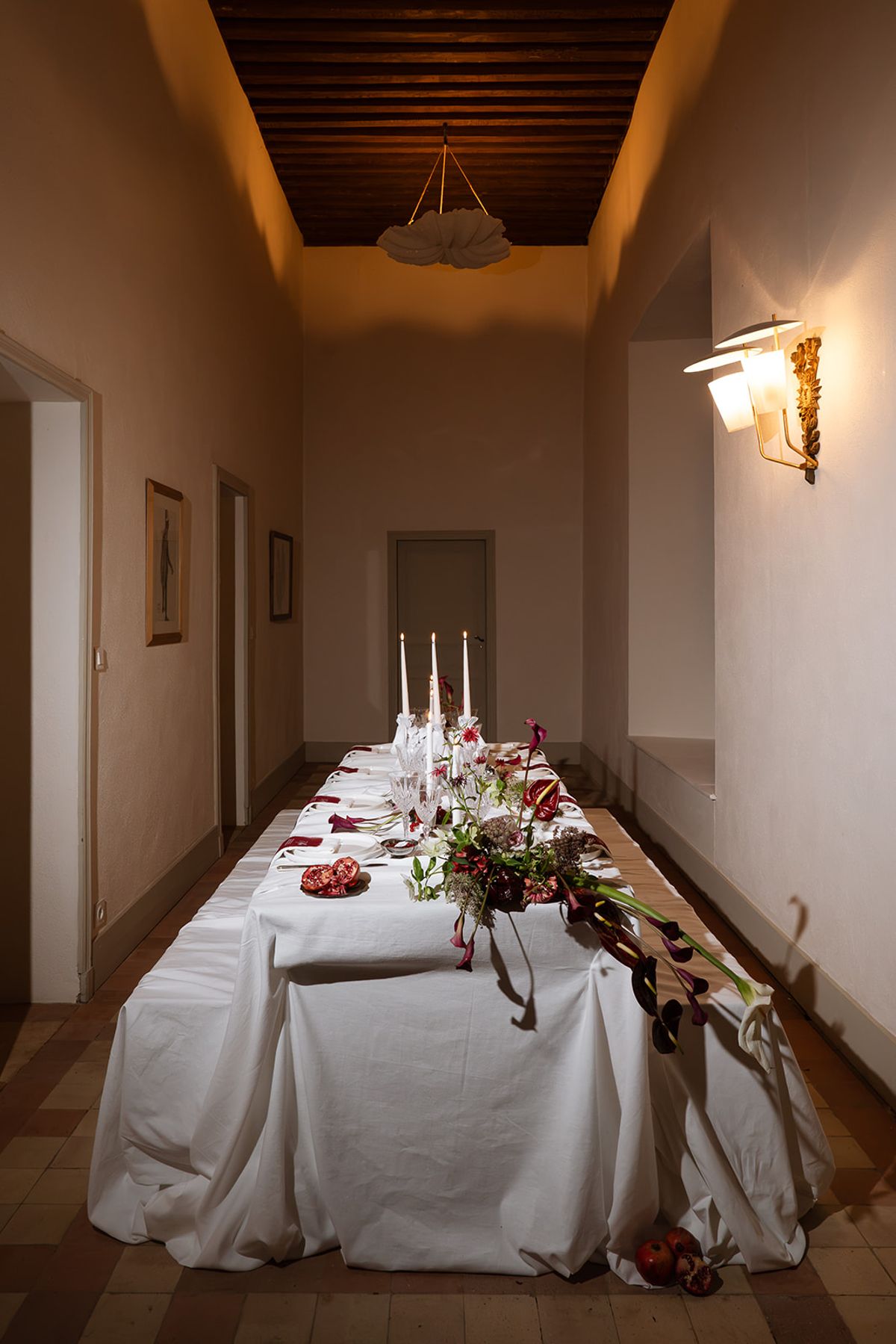 Long candlelit dinner table set in a corridor at Château de Savignac-Mona