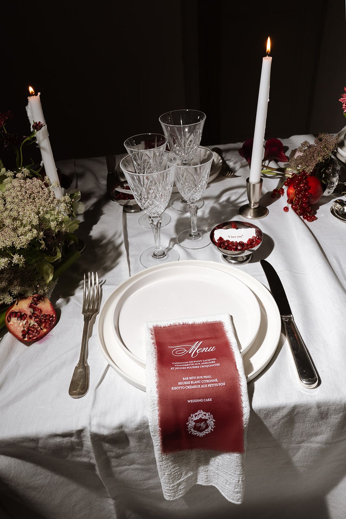 Candlelit place setting with a burgundy menu card and crystal glasses