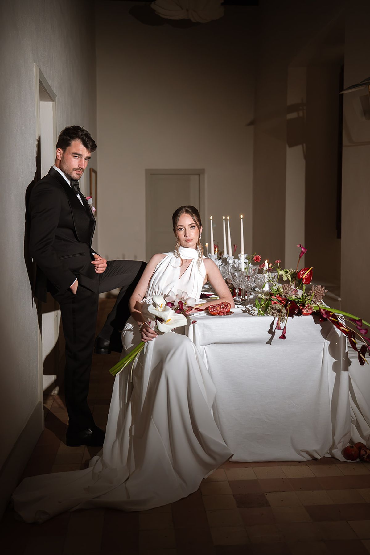 Bride seated at the dinner table with the groom standing beside her