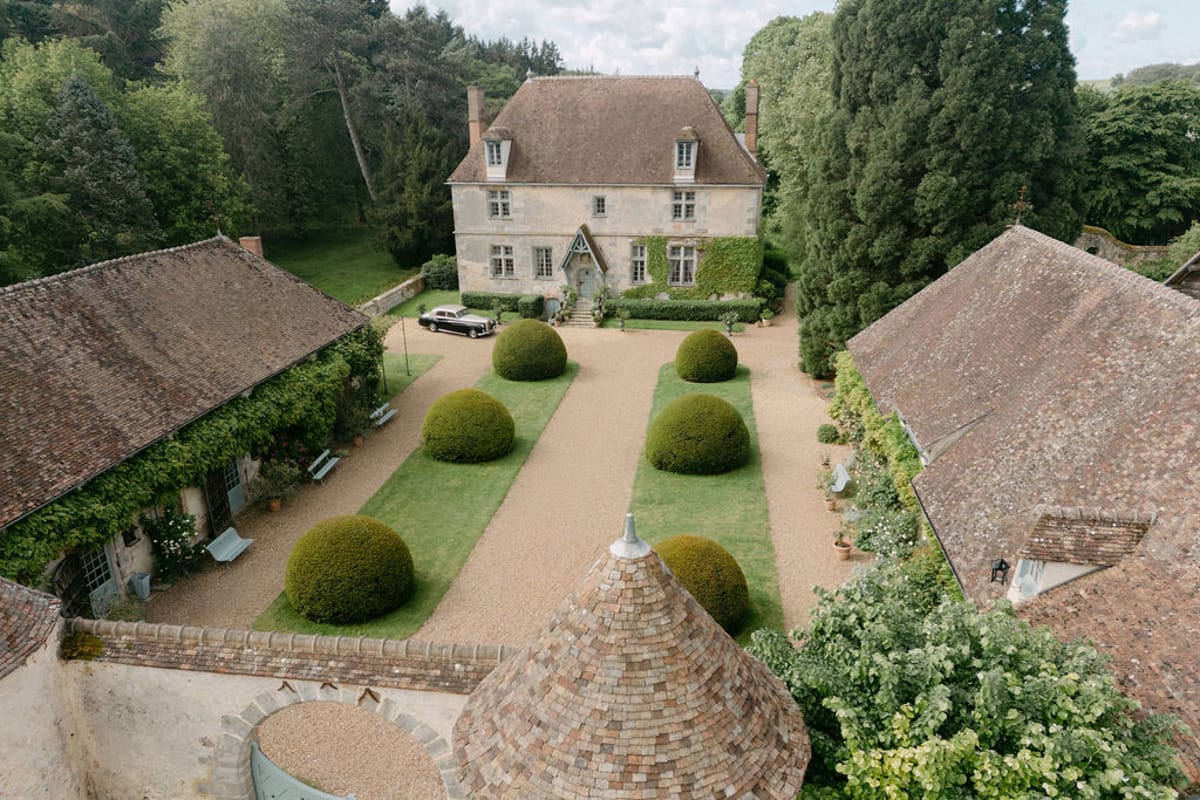 Aerial view of Manoir de Vacheresses' manicured gardens and stone facade, late spring.