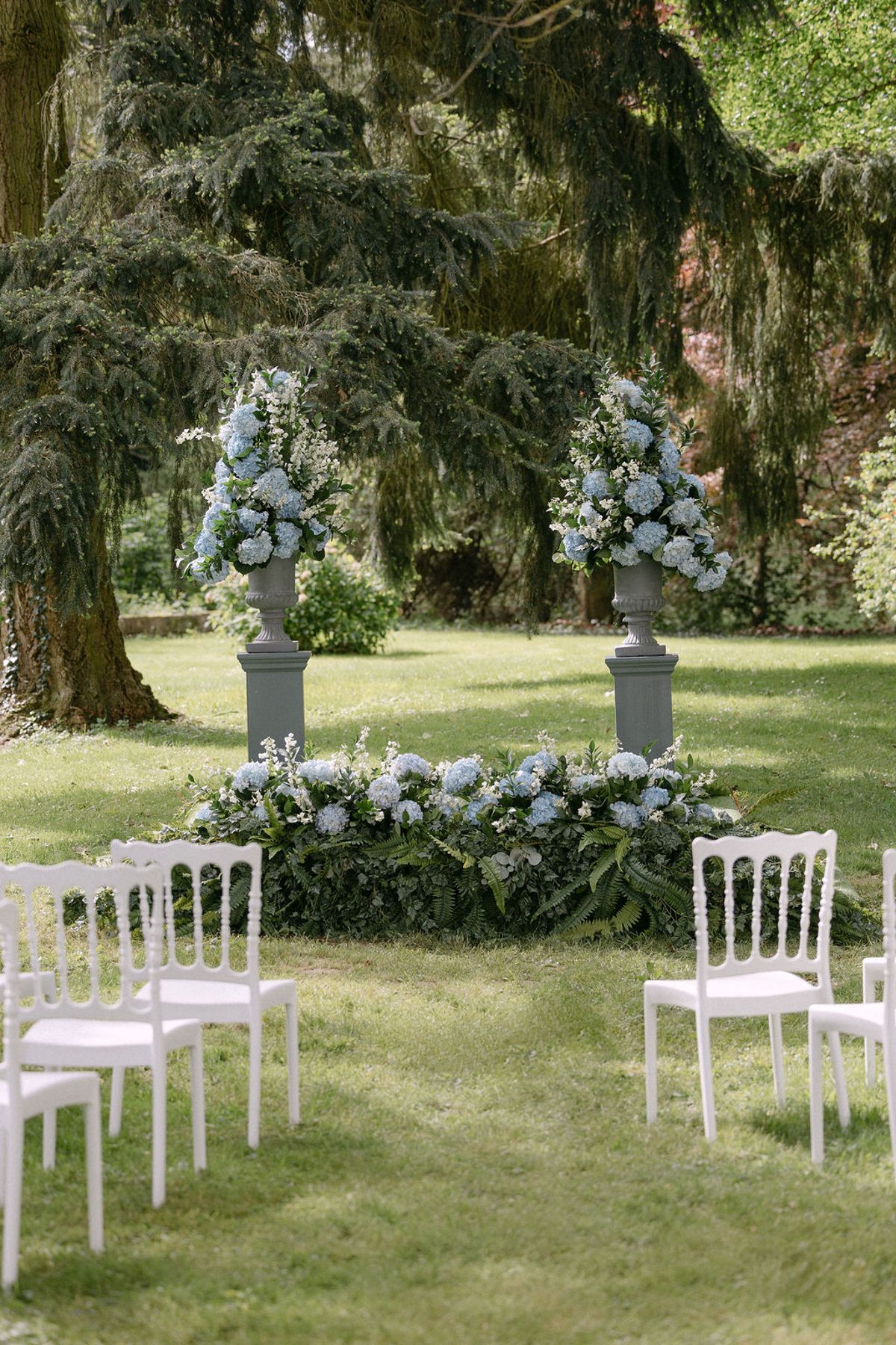 Blue and white floral urns flanking the outdoor ceremony aisle at Manoir de Vacheresses.