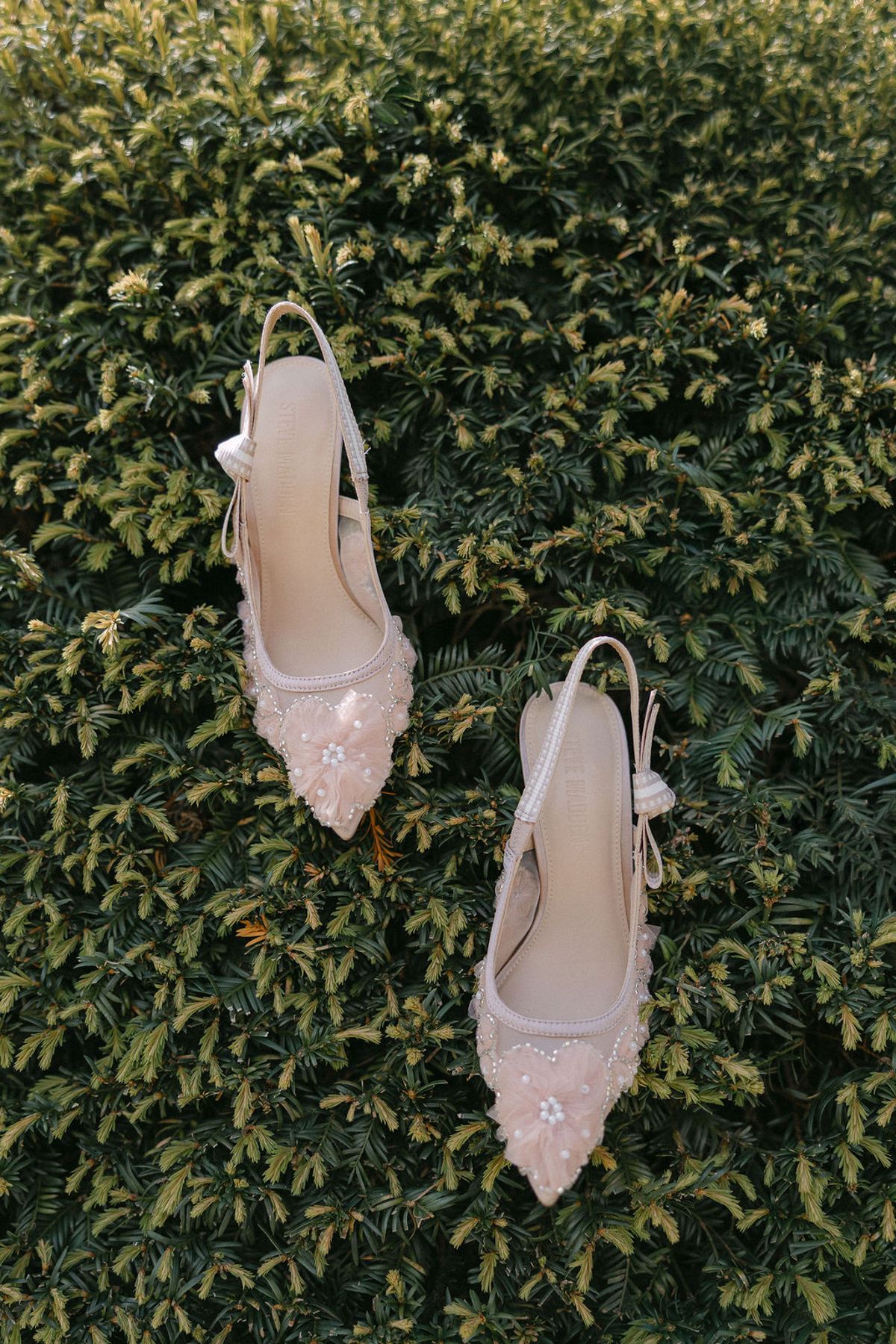 The bride's embellished shoes set against clipped garden hedging.
