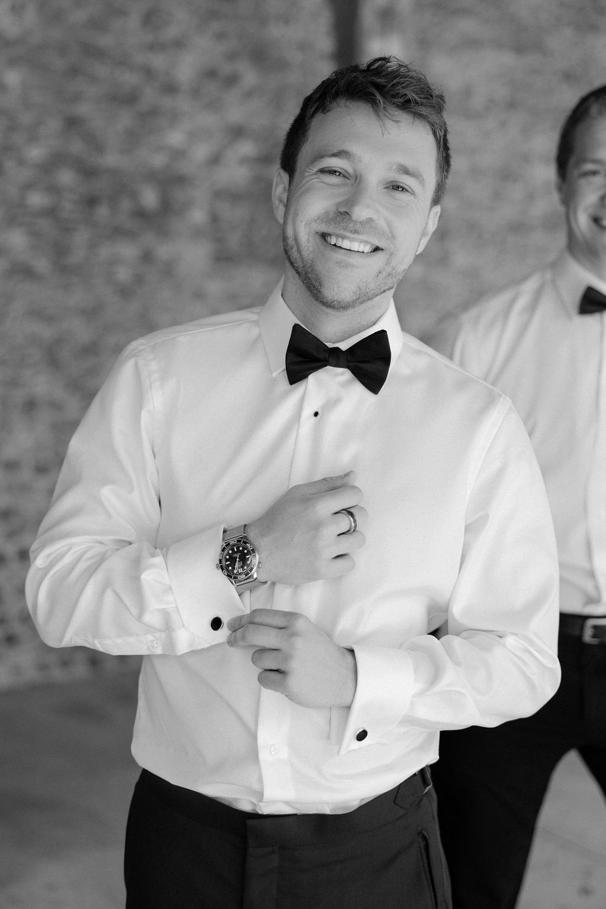 The groom fastening his cufflinks in black and white, getting ready.