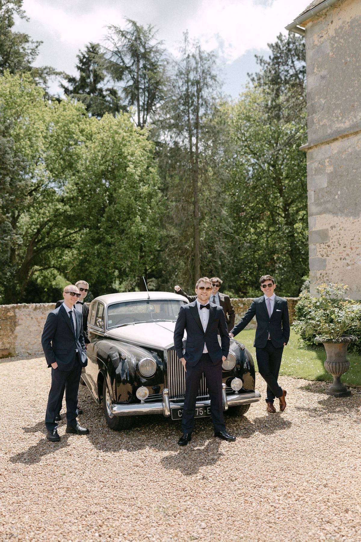 The groomsmen posed beside a vintage car in the grounds of Manoir de Vacheresses.