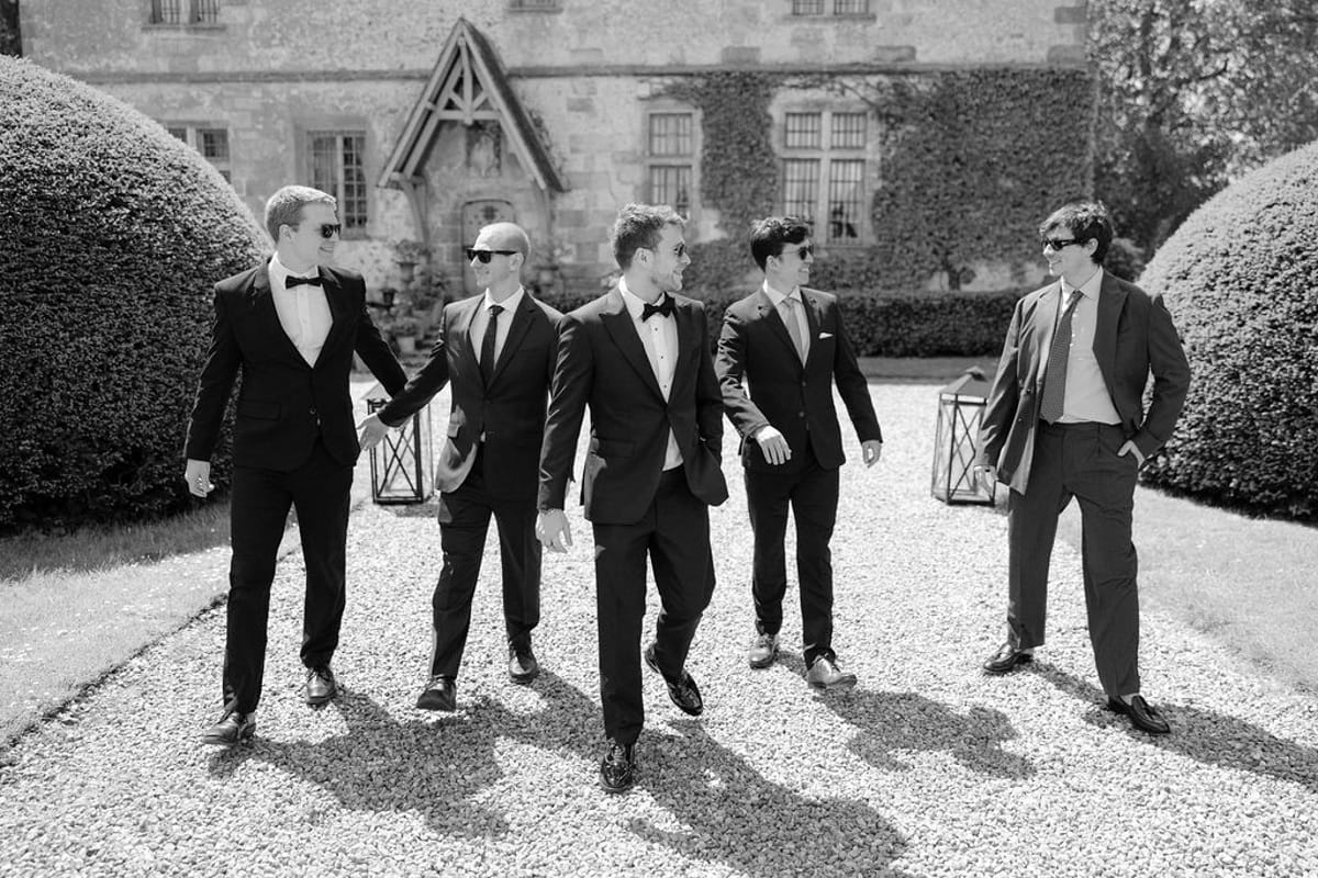 The groom and groomsmen walking together in a row, black and white.