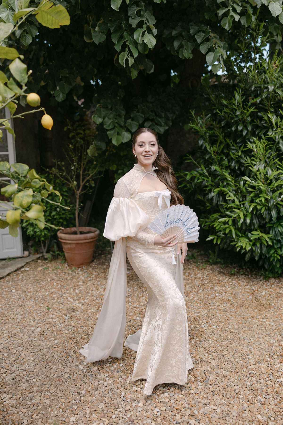 A bridesmaid in a fan-print dress posed beside a potted lemon tree.