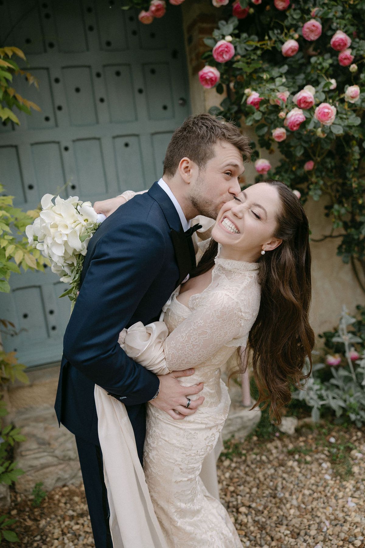Jonathan kissing Olivia's forehead as she holds her bouquet, close portrait.