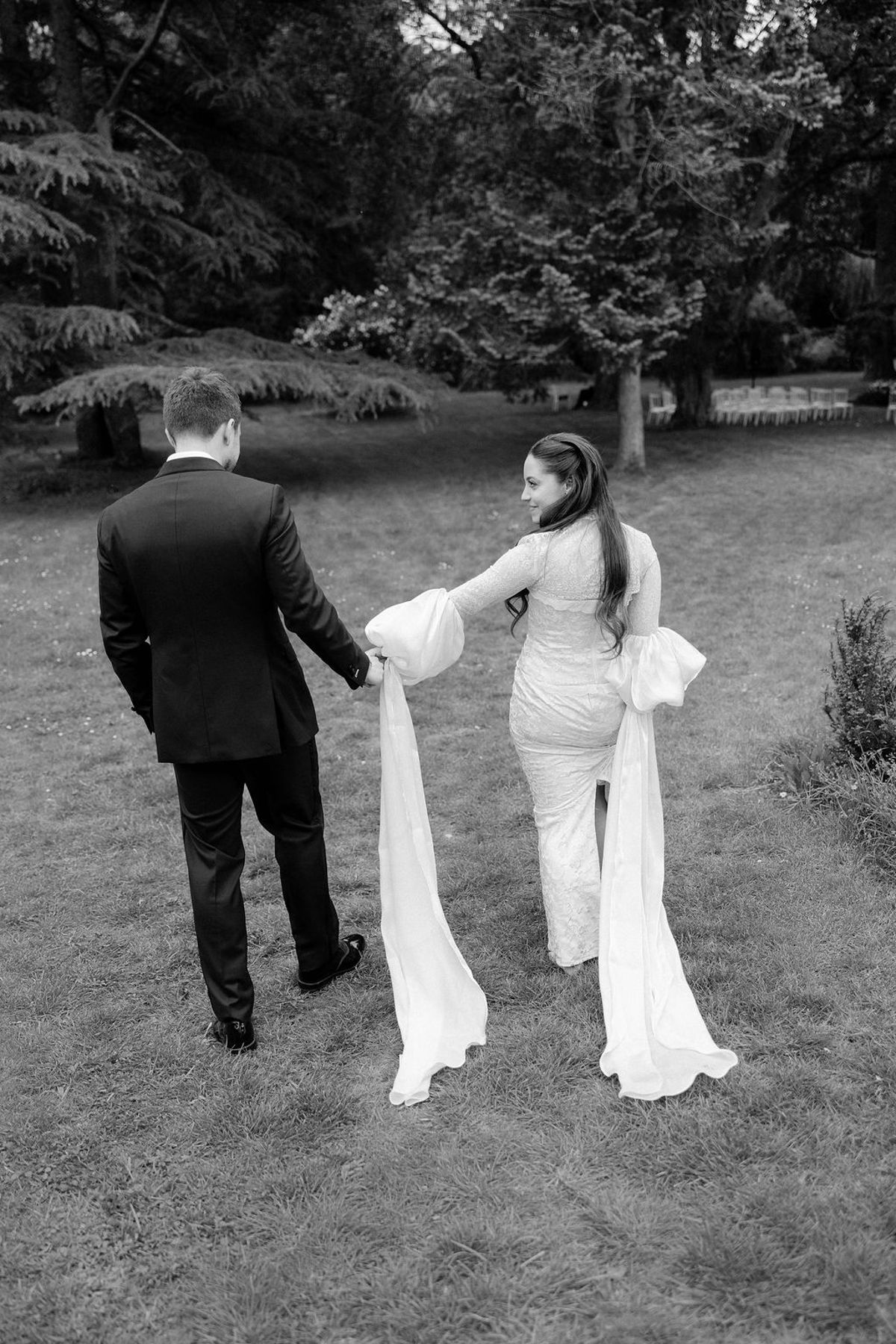 Olivia and Jonathan walking hand in hand away from camera, black and white.