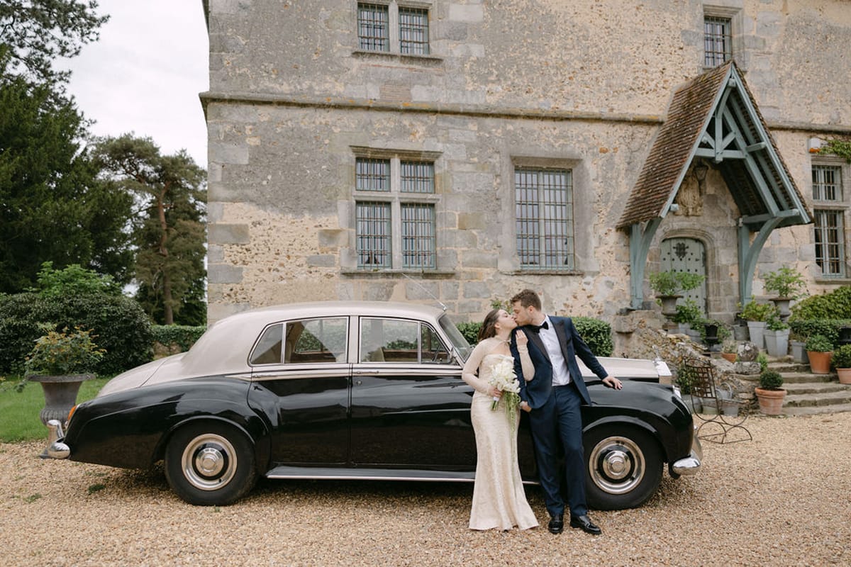 Olivia and Jonathan beside the vintage car outside the manor.