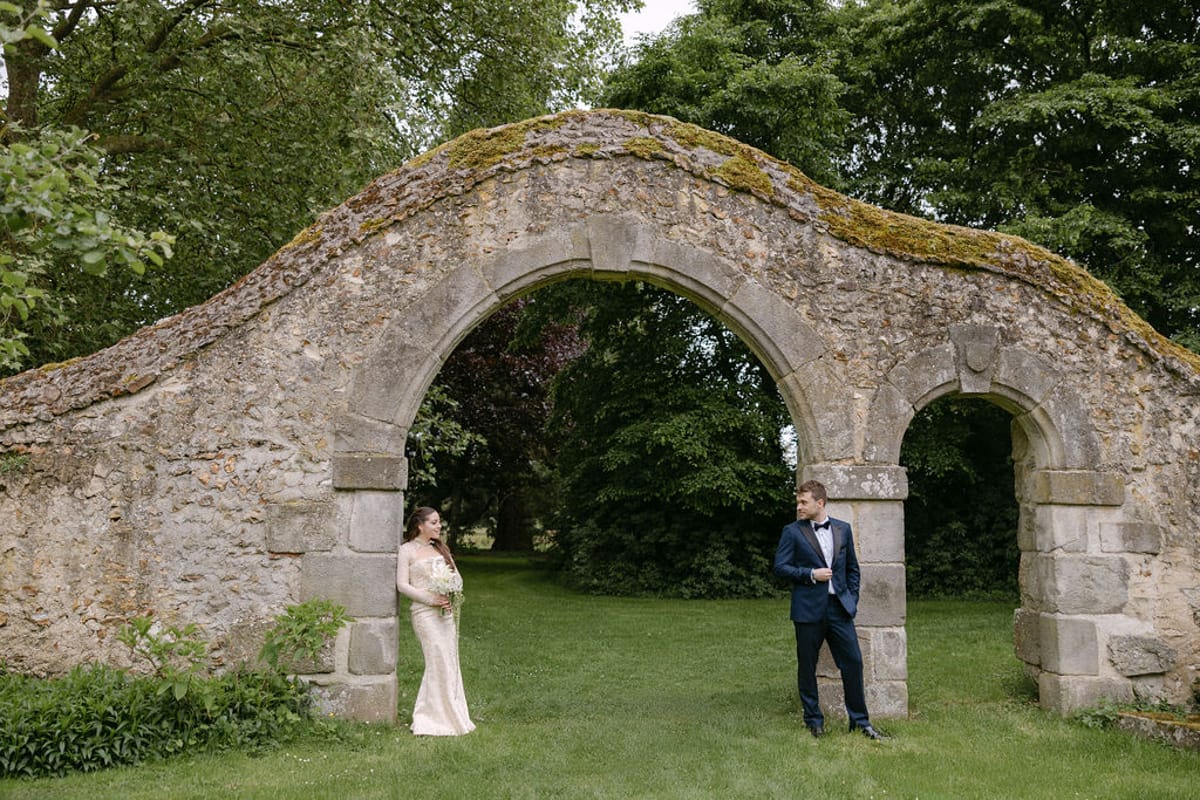 Olivia and Jonathan standing together beneath a stone archway on the grounds.