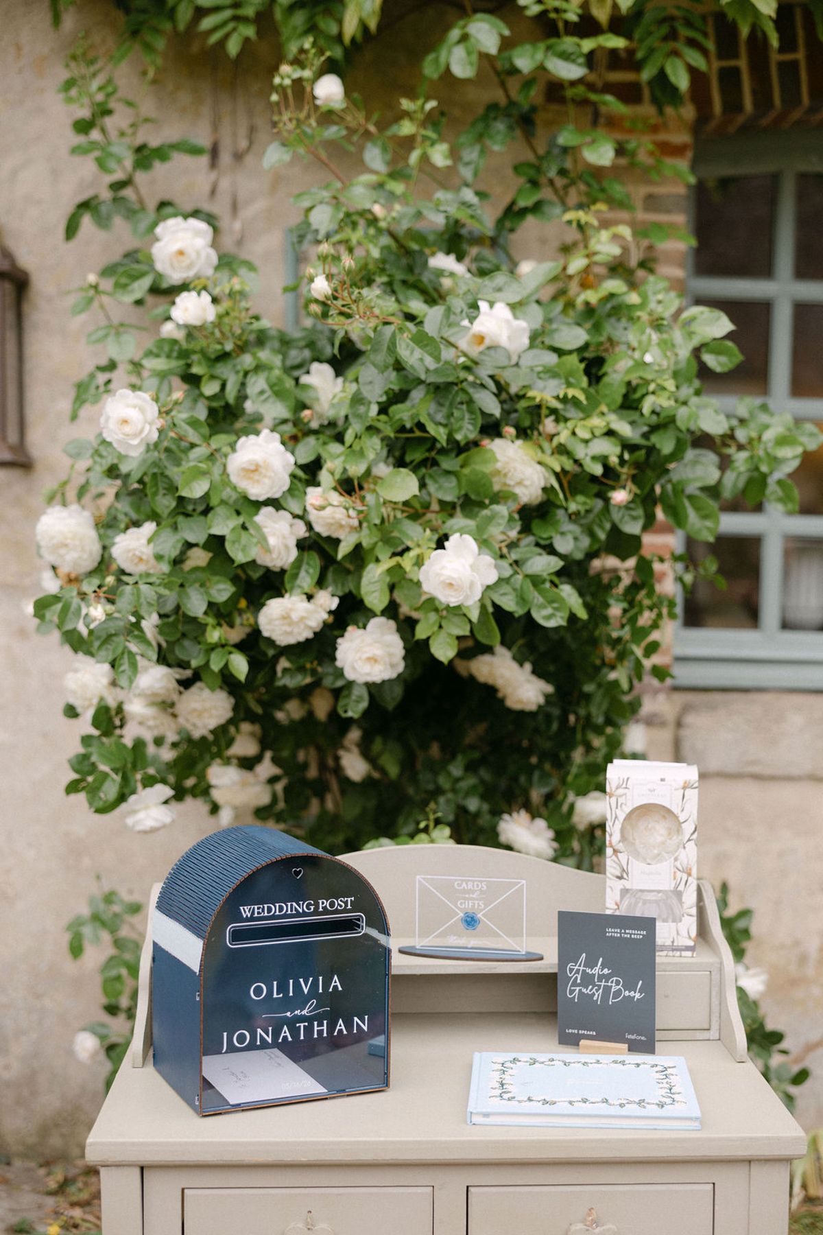 White climbing roses against the manor's stone wall.