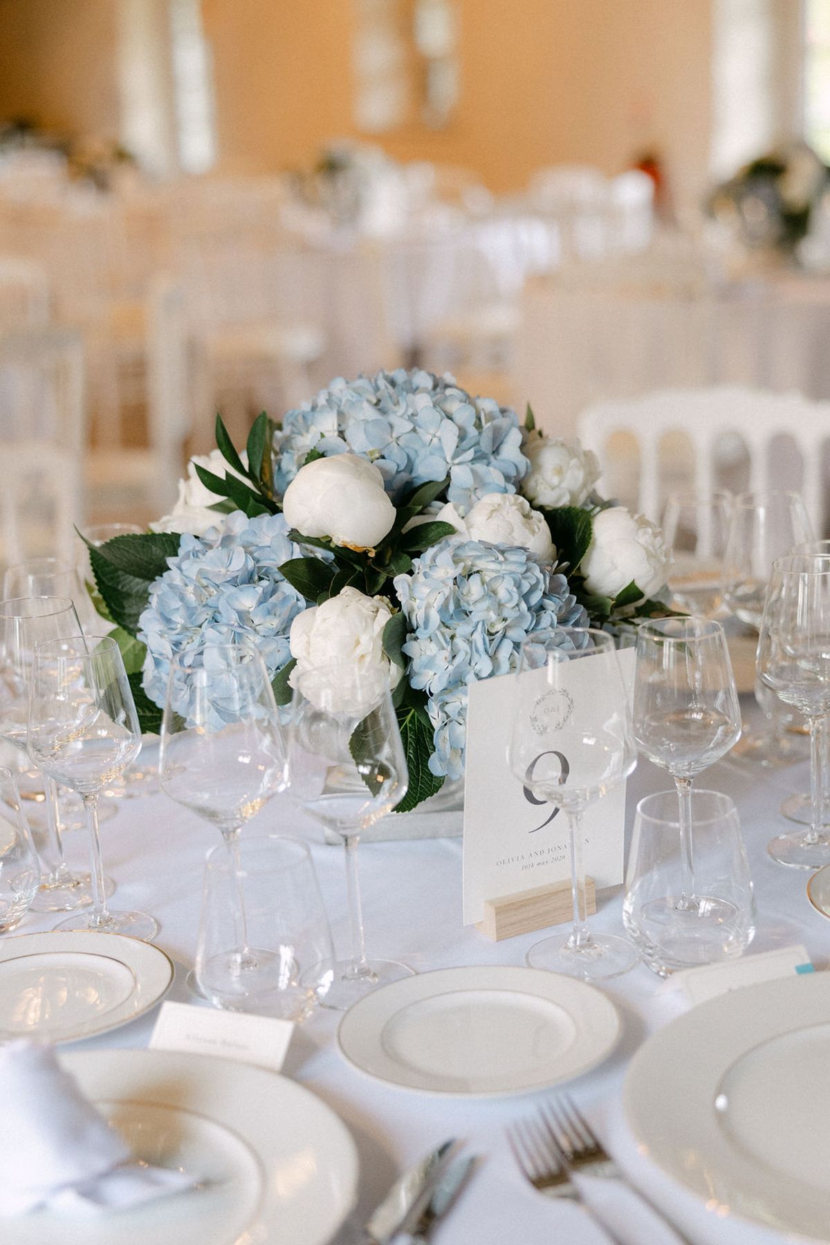 Reception table setting with a blue and white floral centrepiece and numbered place card.