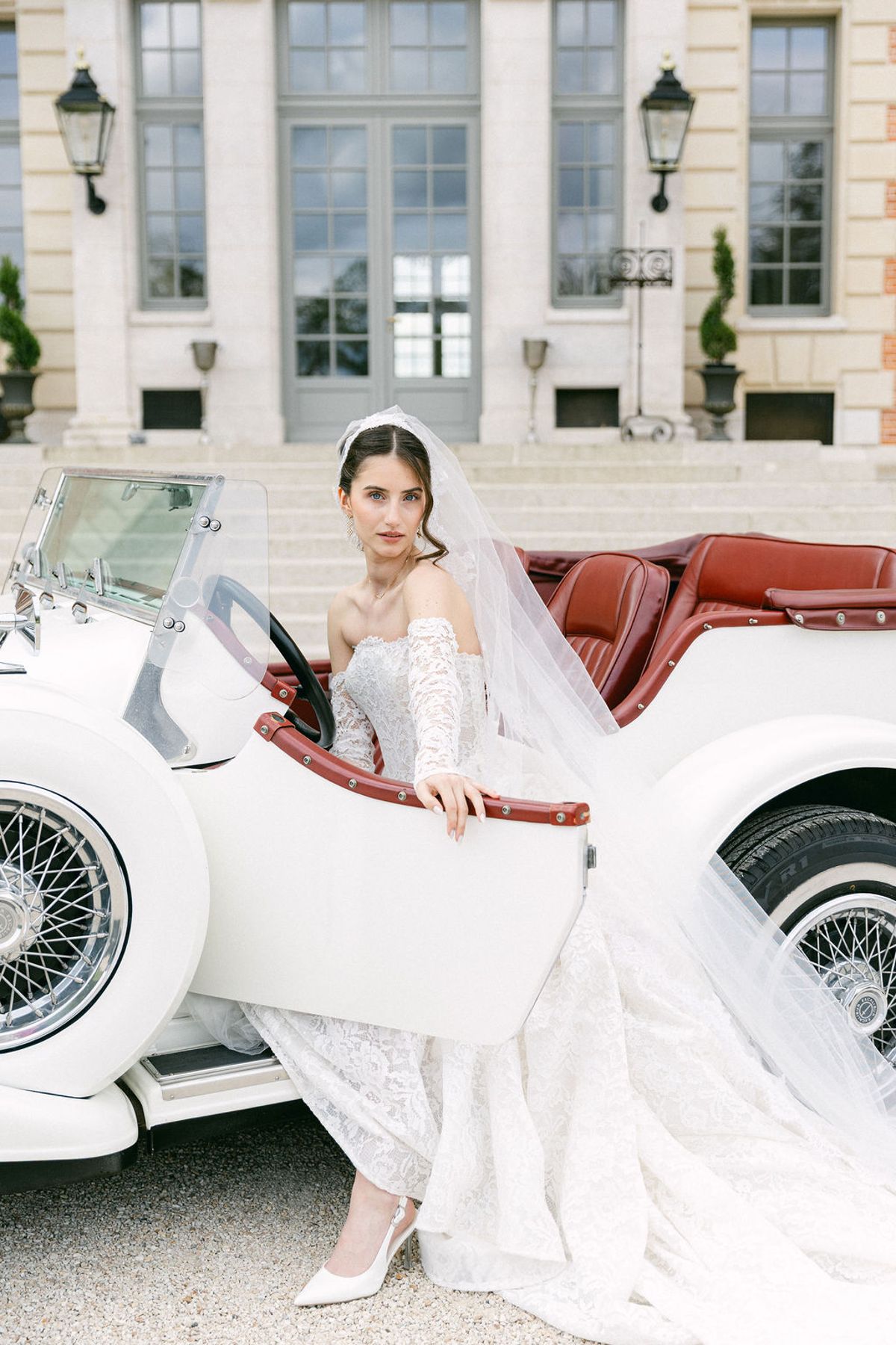 Bride steps down from the running board of the white vintage car