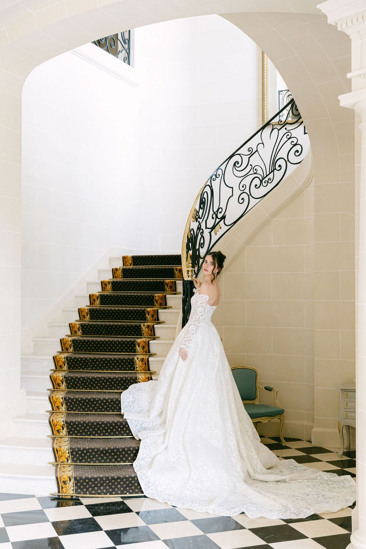 Bride climbing the chateau's curved staircase with her train behind her