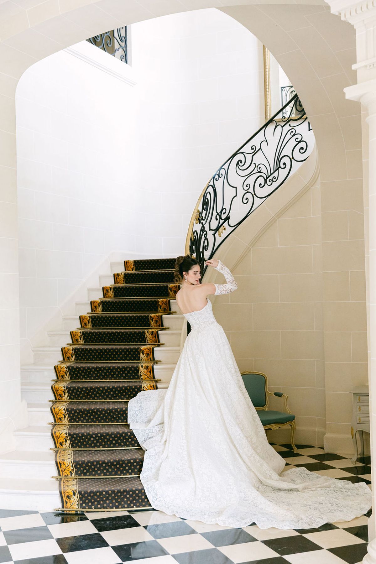Bride on the lower steps of the chateau's iron-railed staircase